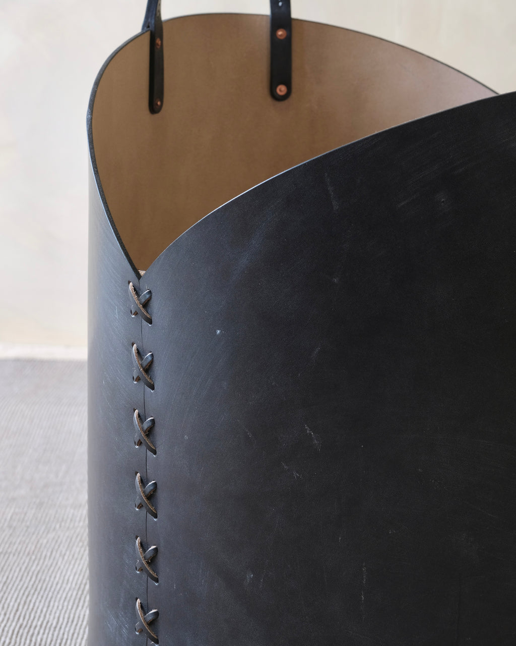 Close-up of a black leather basket with visible stitching on a light background