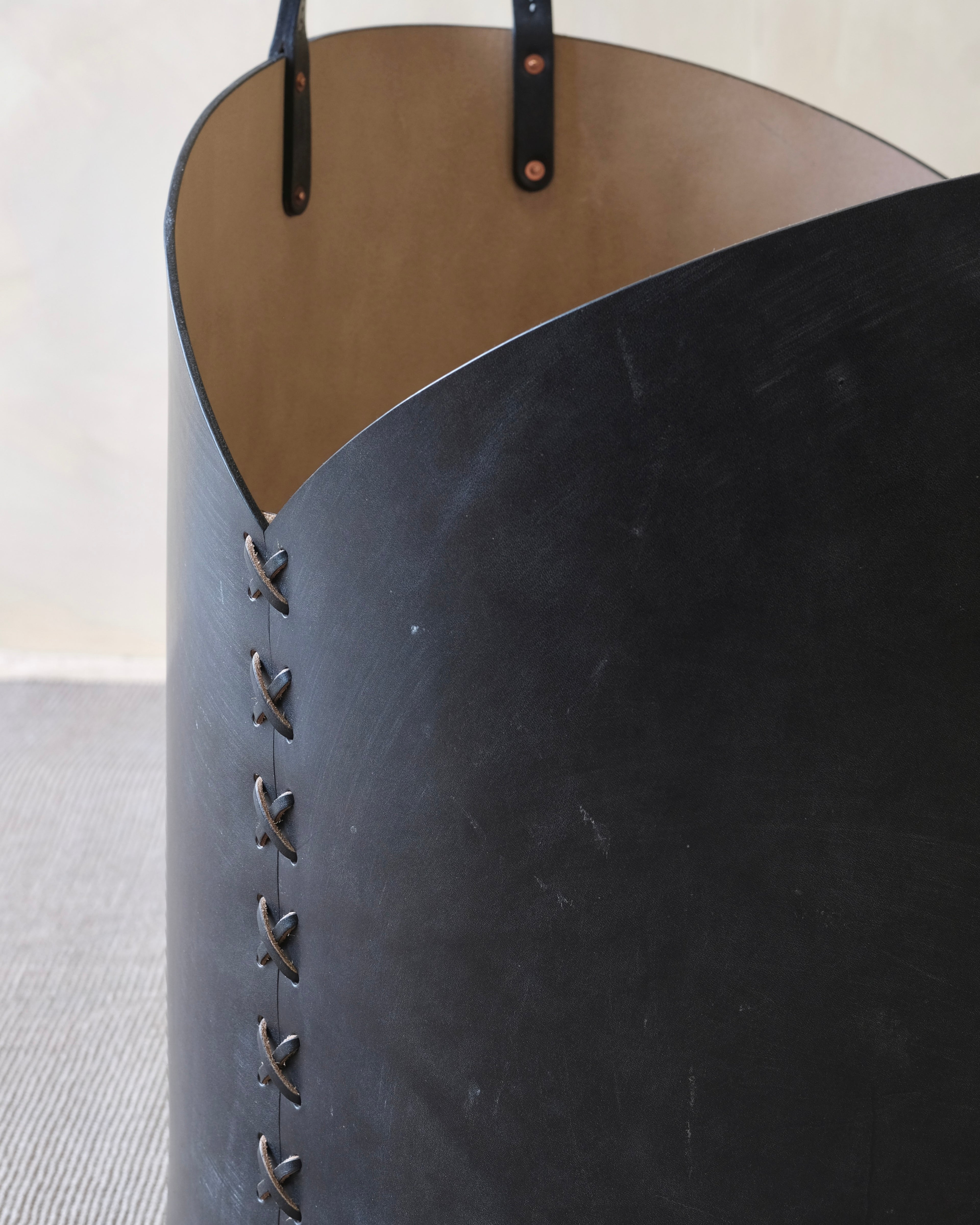 Close-up of a black leather basket with visible stitching on a light background