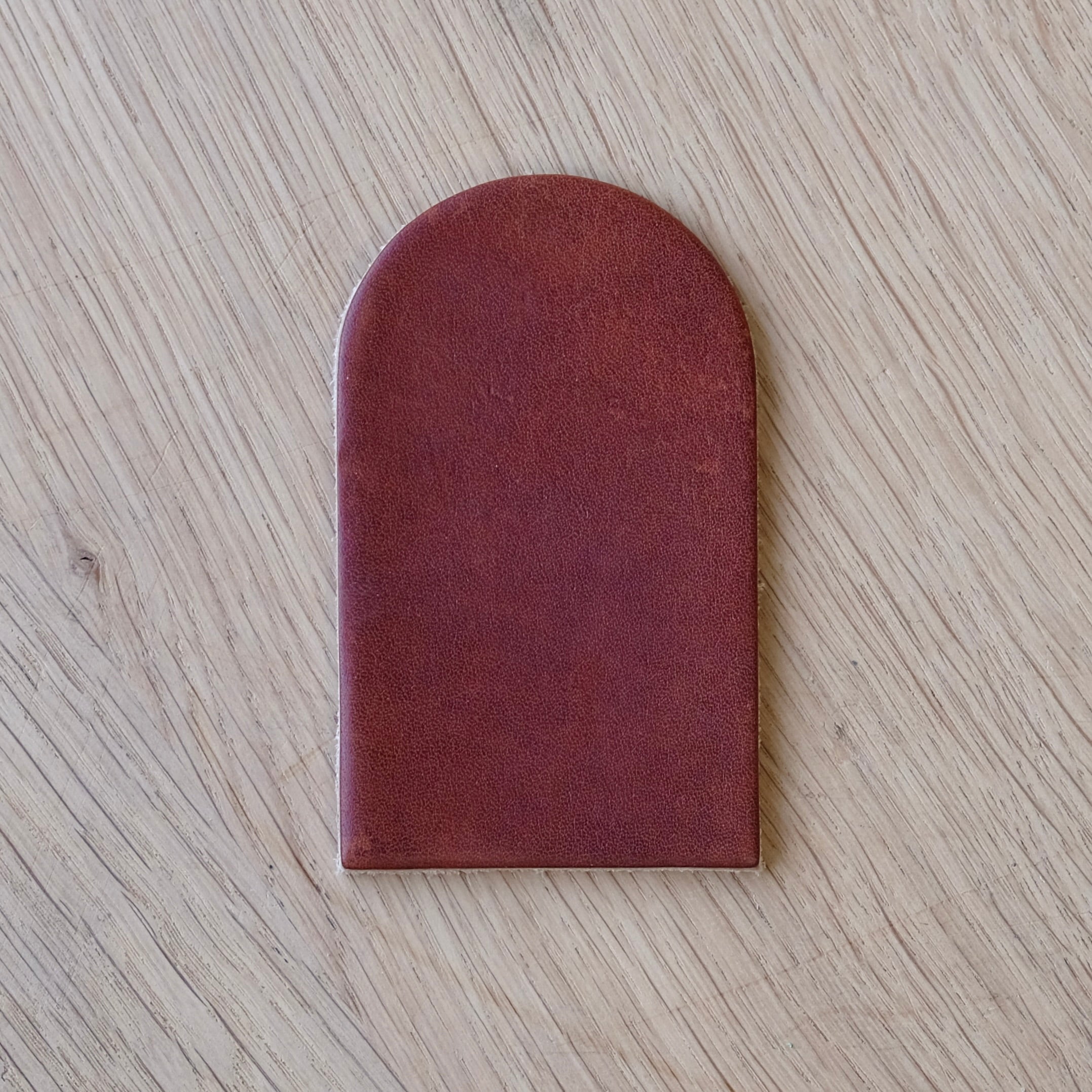 Dark brown leather swatch on a light wood grain surface