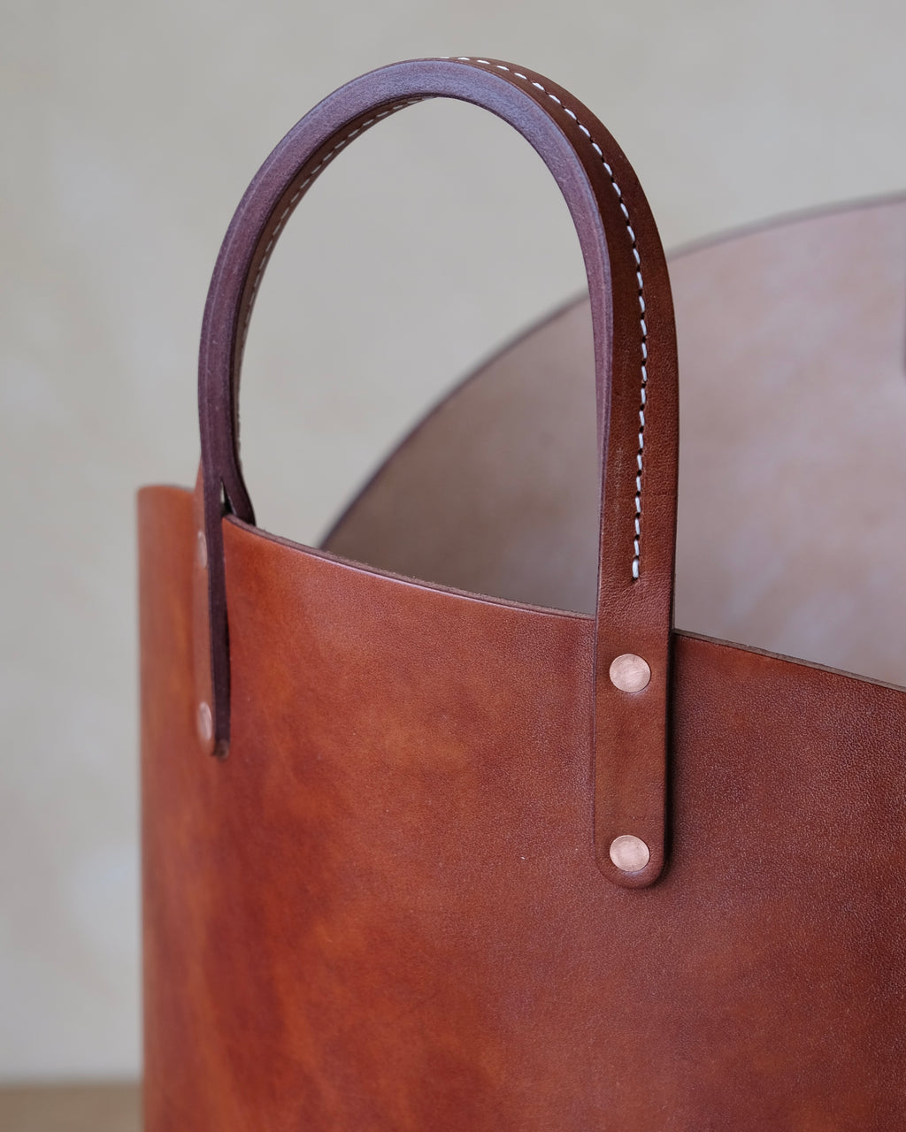 Close up of hand made stitched handle on dark brown leather log basket