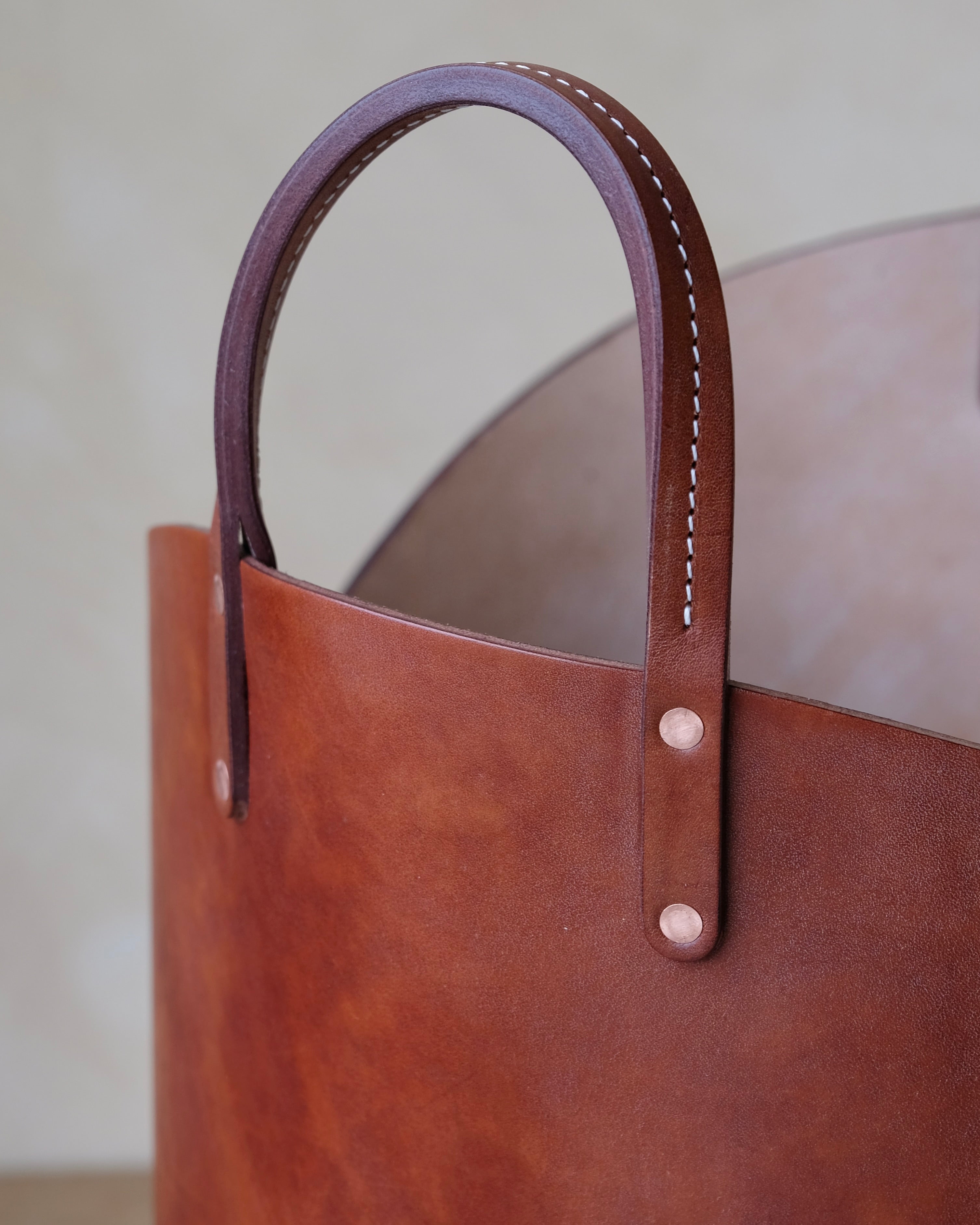 Close up of hand made stitched handle on dark brown leather log basket