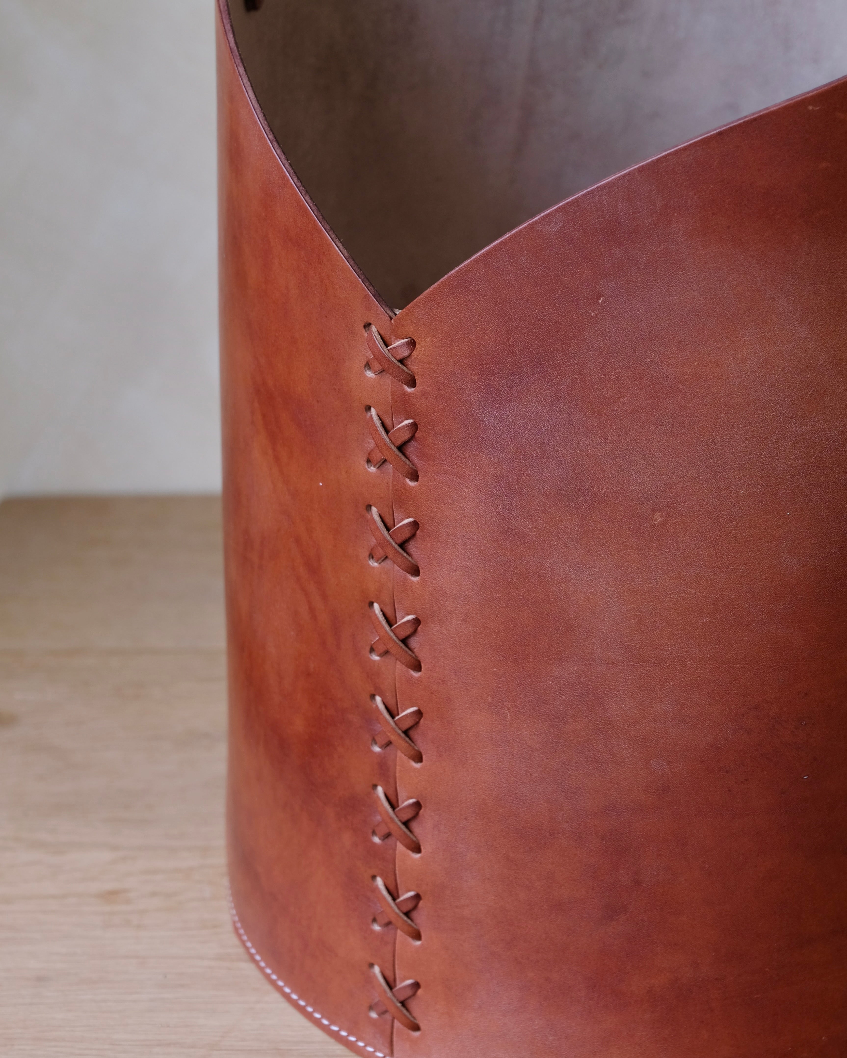 Close-up of a Conker brown leather log basket with leather lacing.