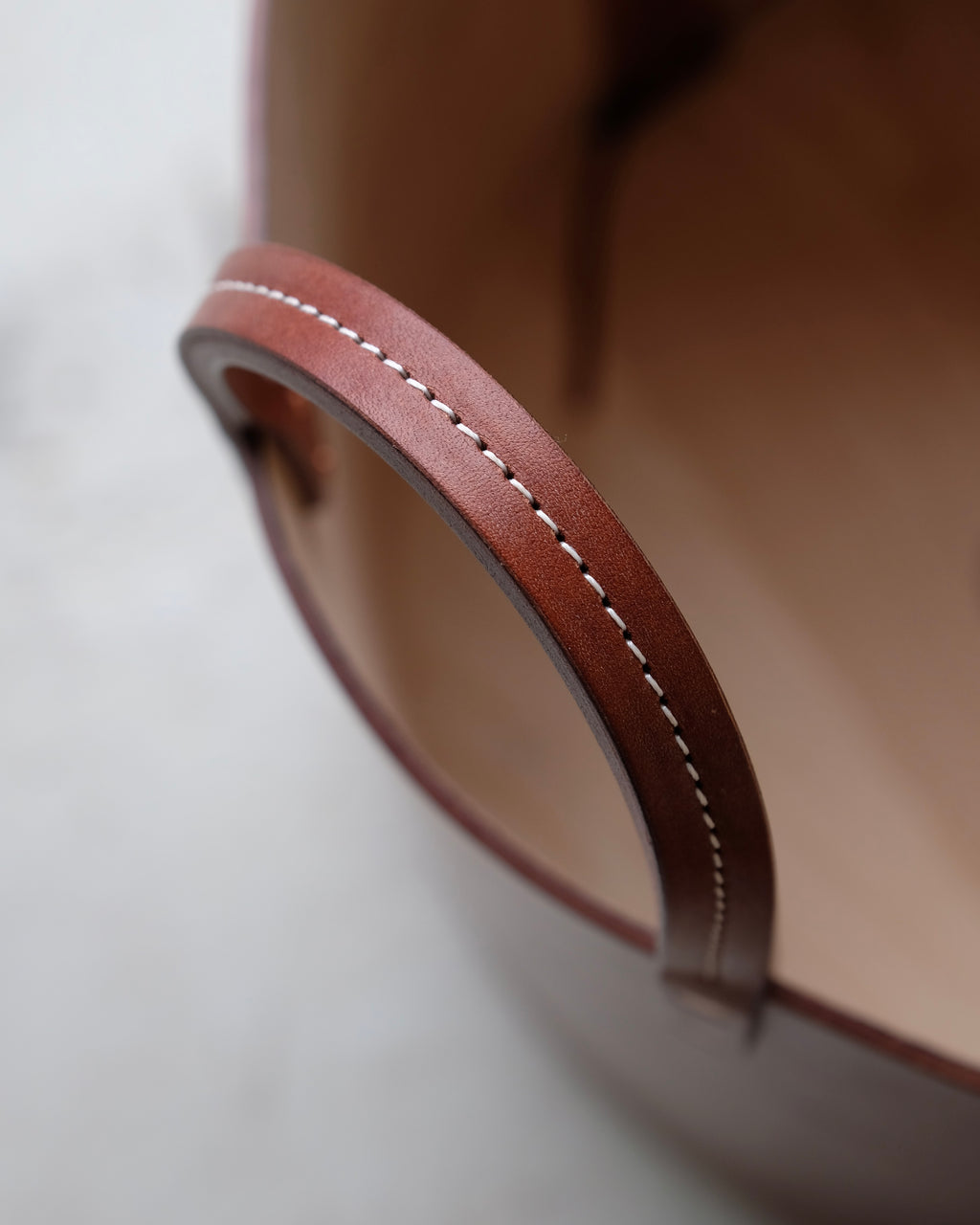 Close up of stitched leather handle of dark brown log basket