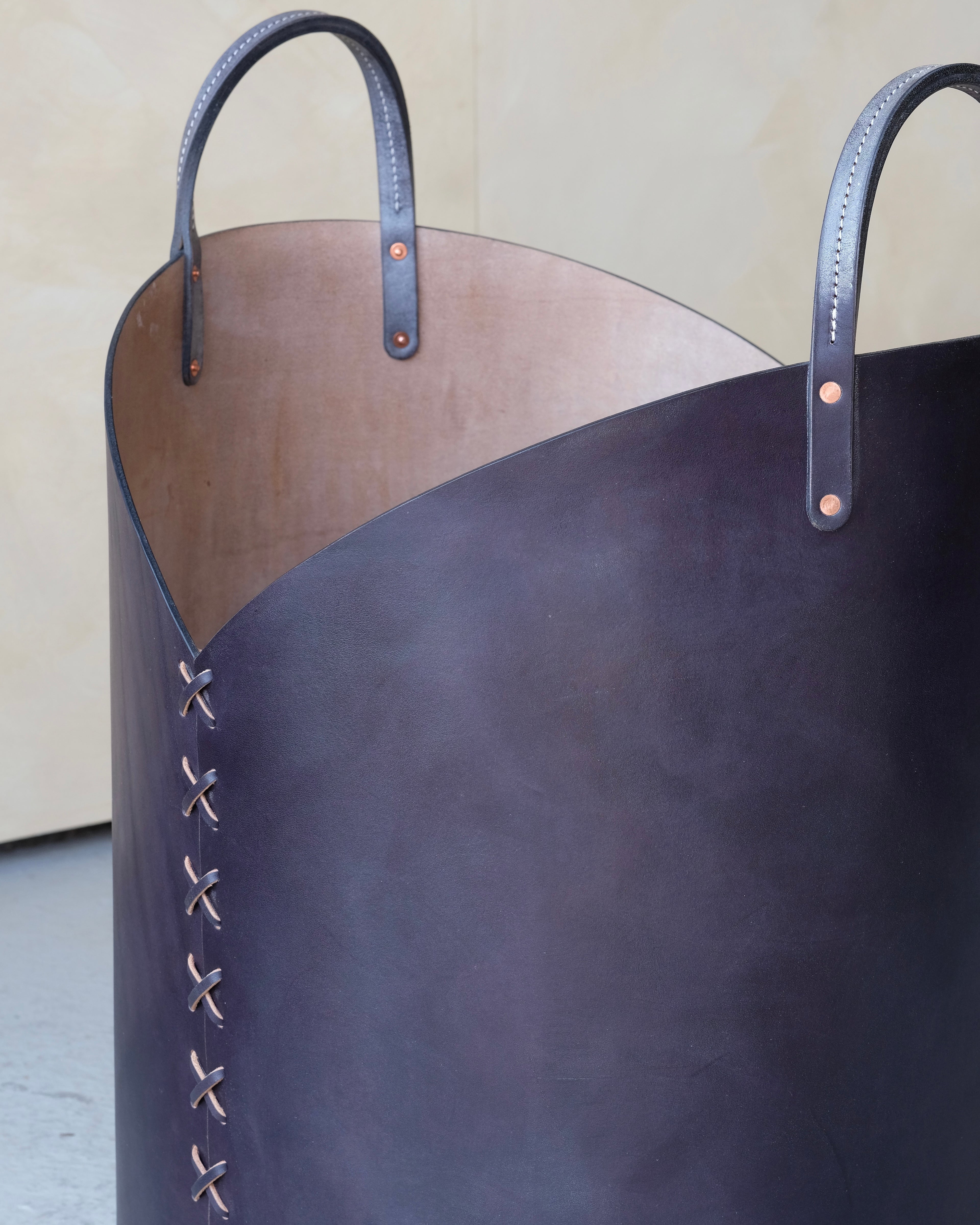 Large dark blue leather basket with handles on a light background