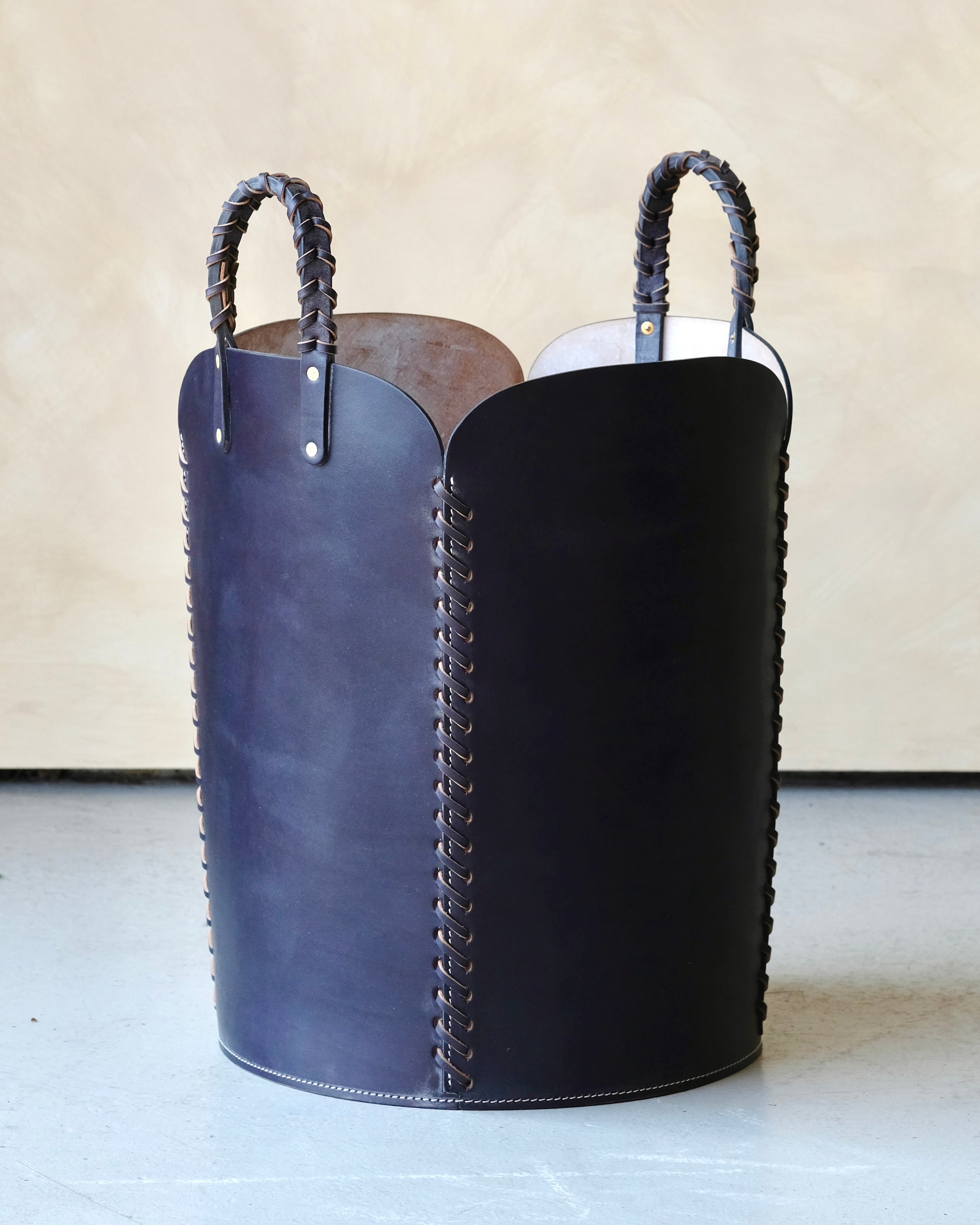 Navy blue leather basket with woven handles on a light background