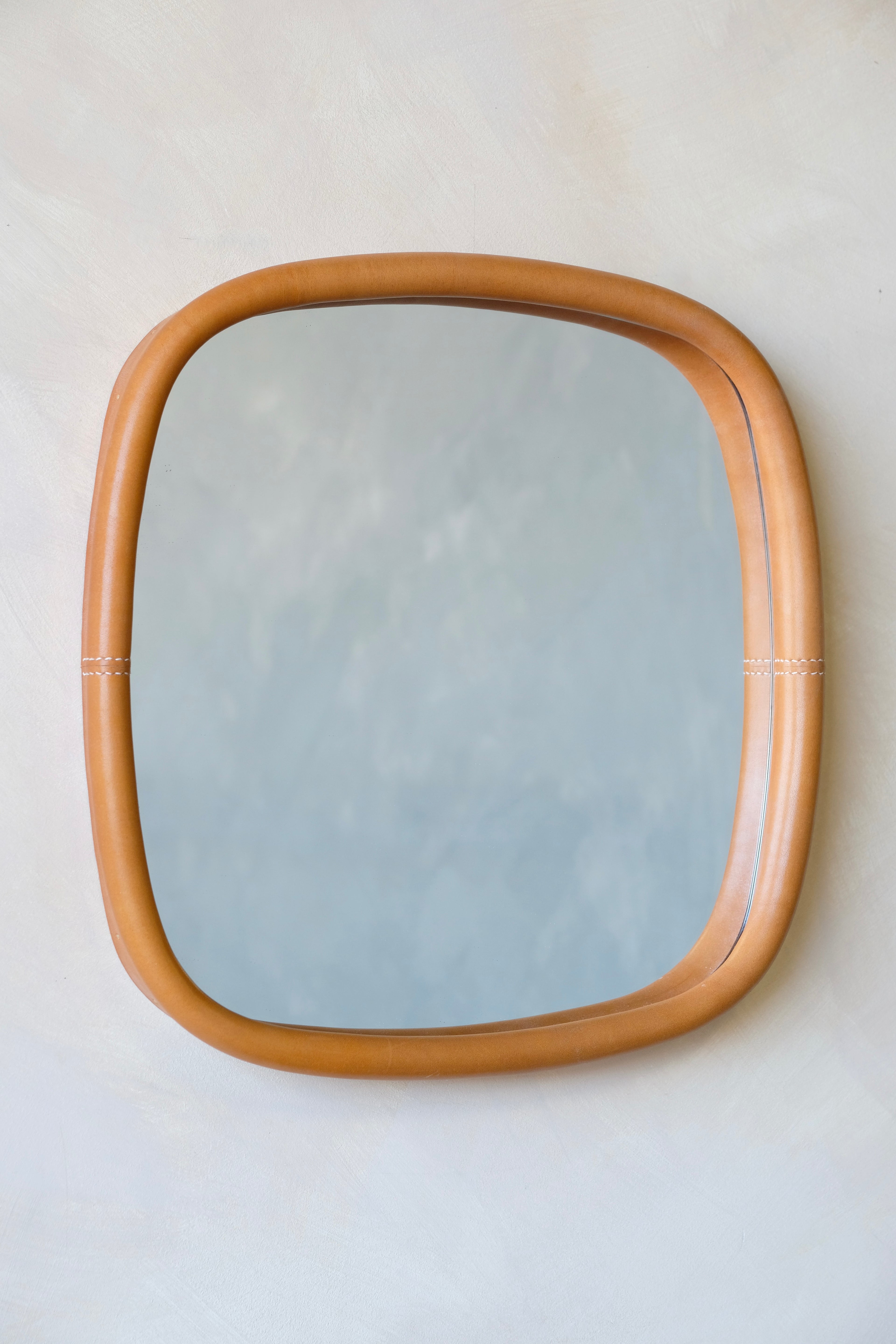 Rectangular mirror with a leather frame on a white wall