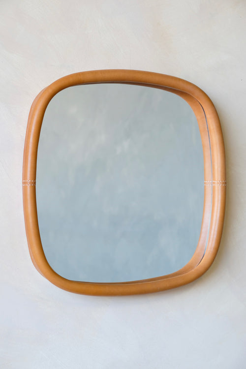 Rectangular mirror with a leather frame on a white wall