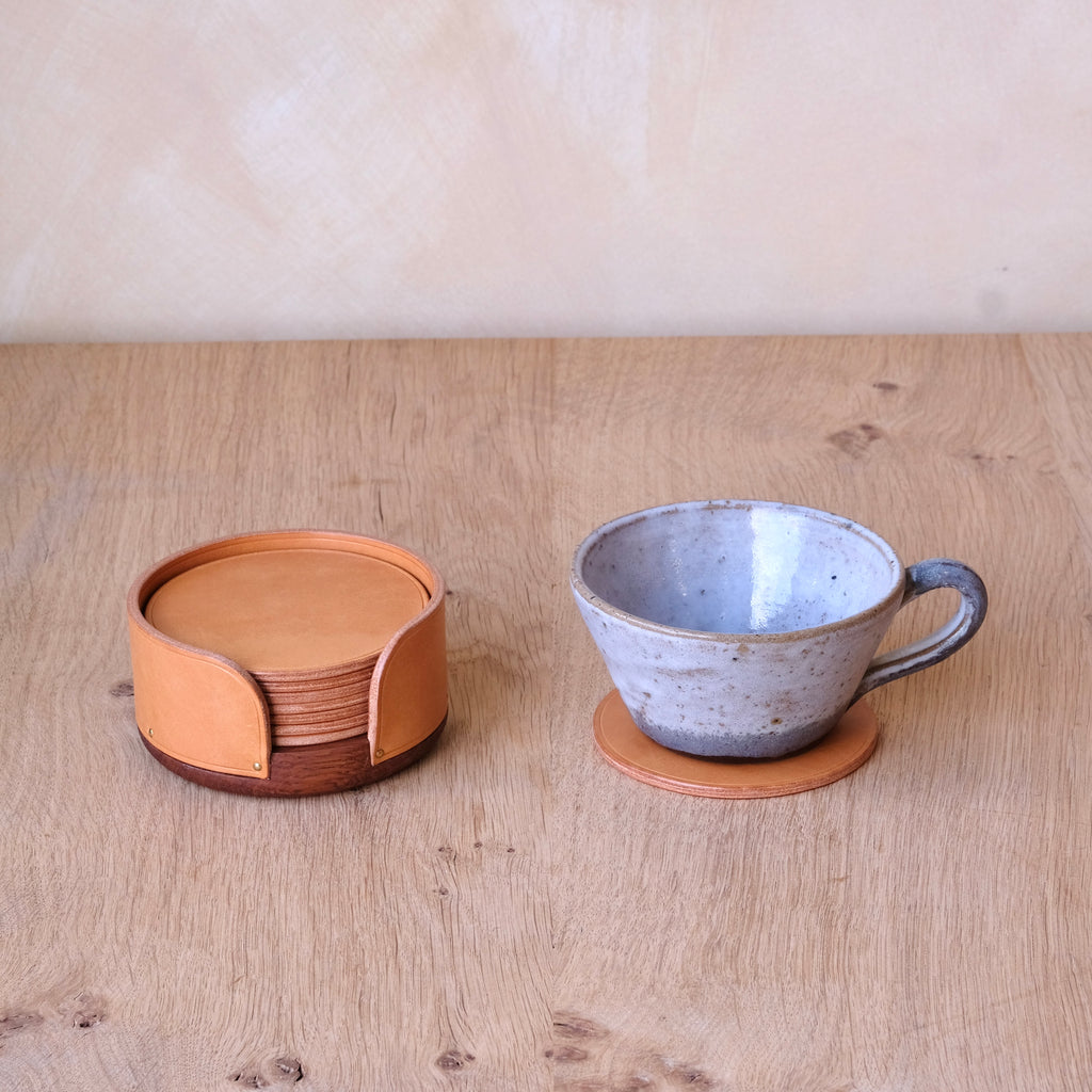 Ceramic cup with saucer and set of coasters on a wooden surface
