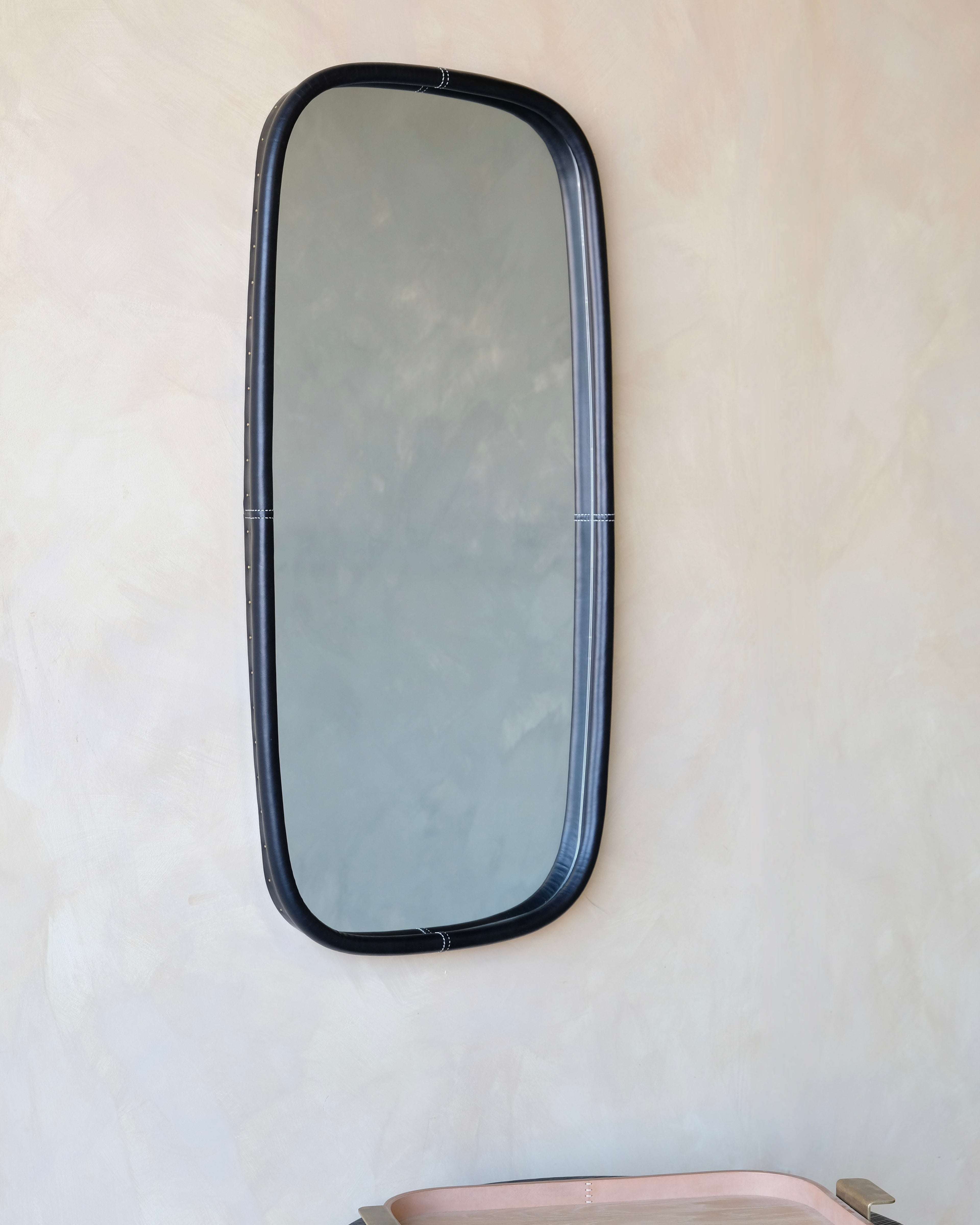 Rectangular mirror with black frame on a beige wall
