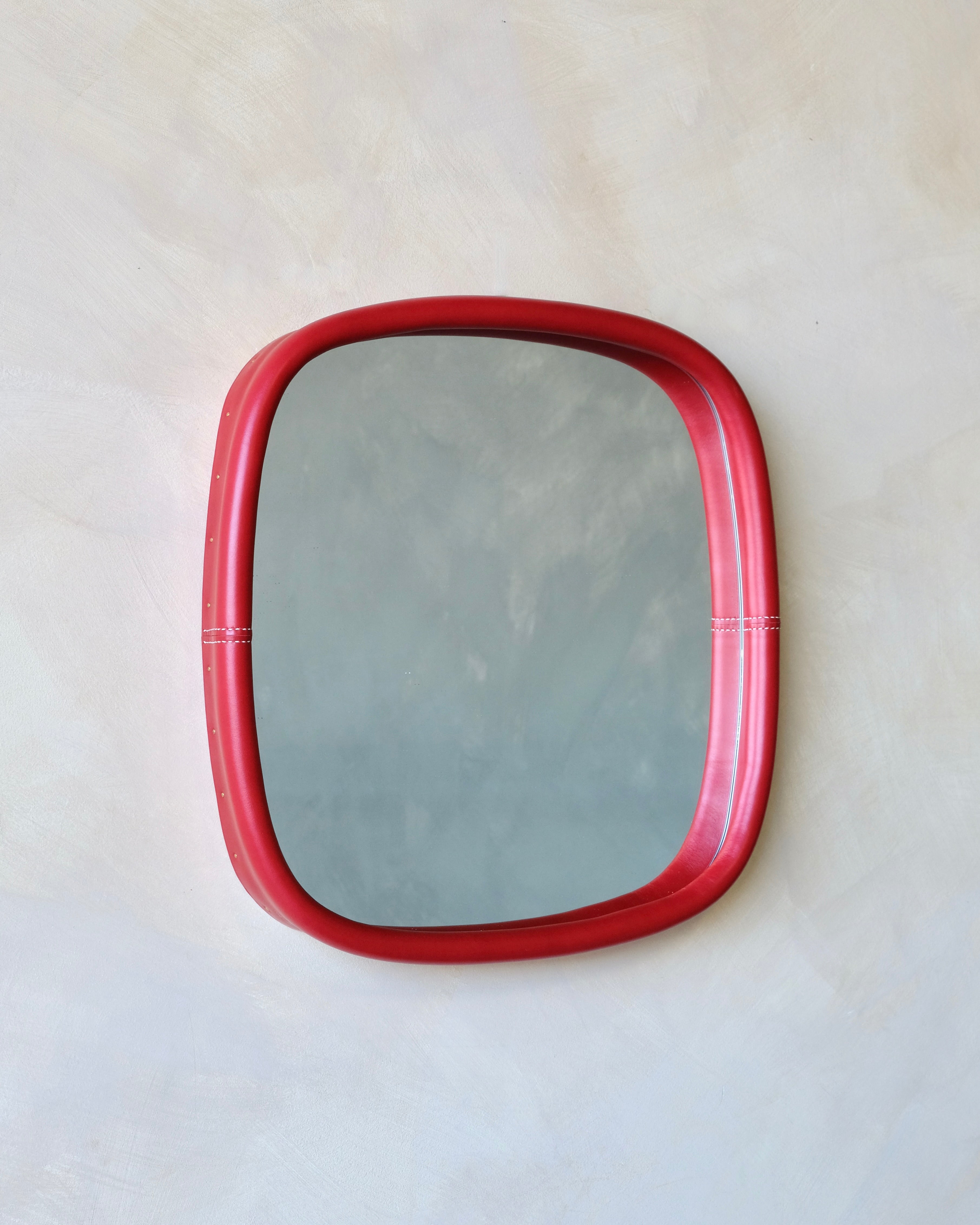 Rectangular mirror with a red leather frame on a white background